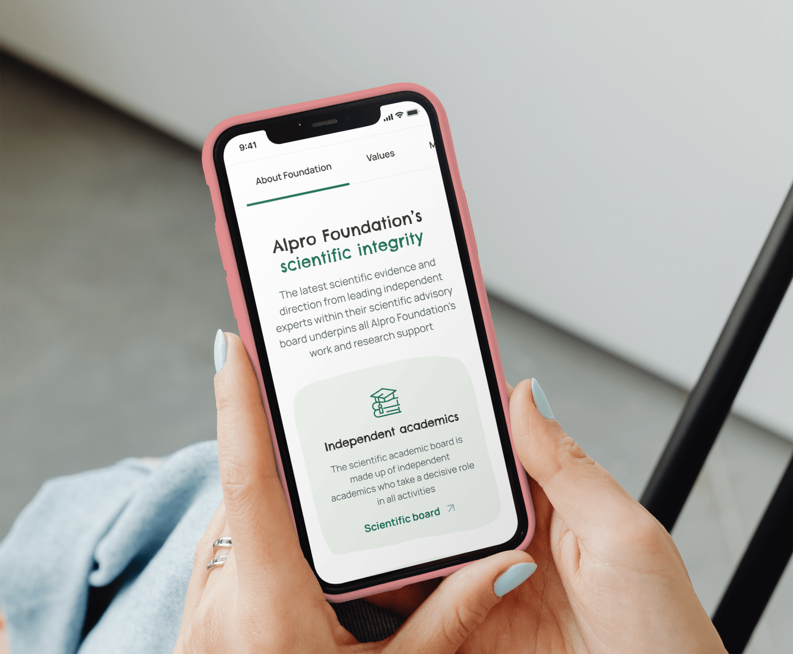 A pink iPhone displays the Alpro Foundation's scientific integrity page, showing information about their independent academic board and research support.
