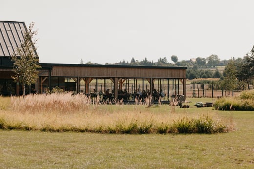 A team gathering takes place in a wooden pavilion surrounded by tall grasses.